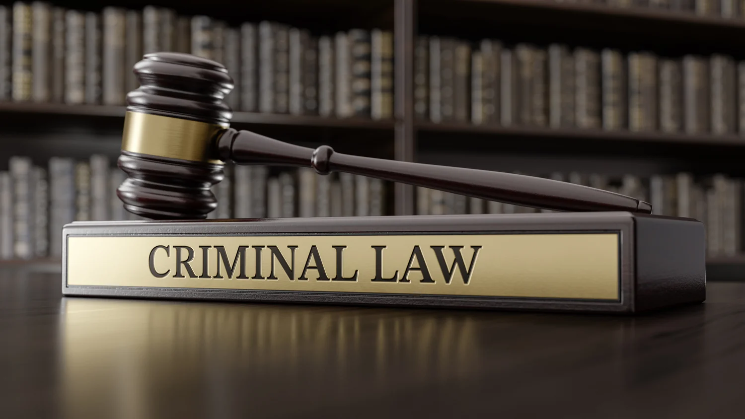 A wooden gavel rests on a rectangular plaque labeled "Criminal Law," with shelves of legal books in the blurred background.
