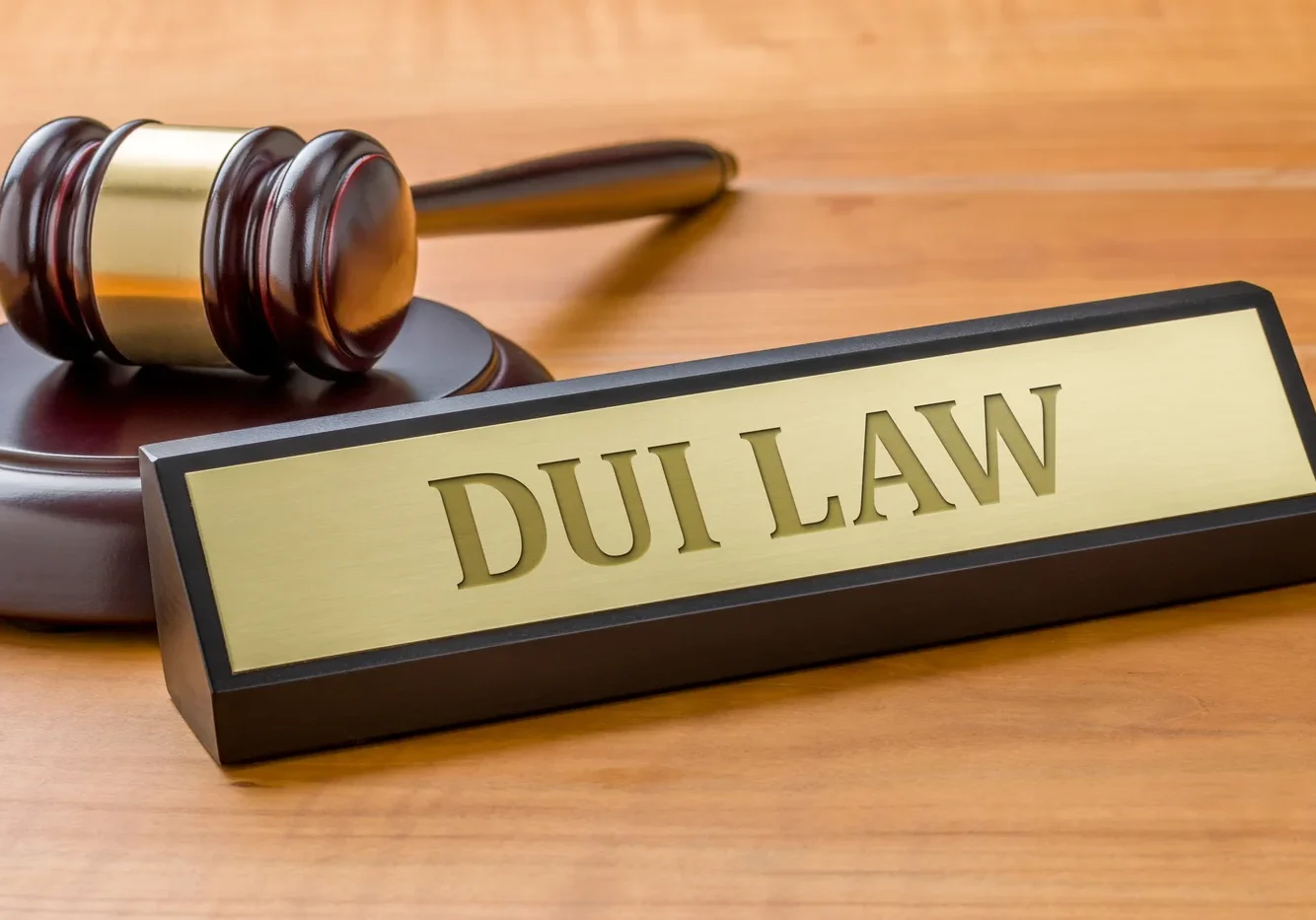 A desk nameplate reads "DUI Law" beside a wooden gavel on a wooden surface.